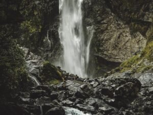 Stunning view of a waterfall tumbling down moss-covered rocks in New Zealand's serene landscape.